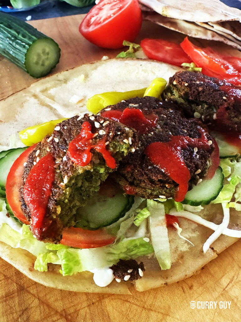 felafel on a flat bread with salad vegetables and sauces.